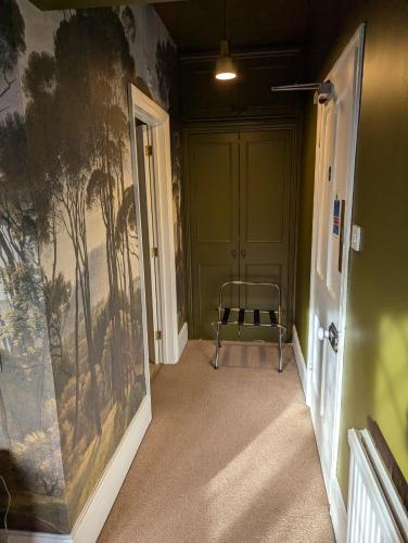 a hallway with a chair and a painting on the wall at The Duke Hotel in Hilmarton