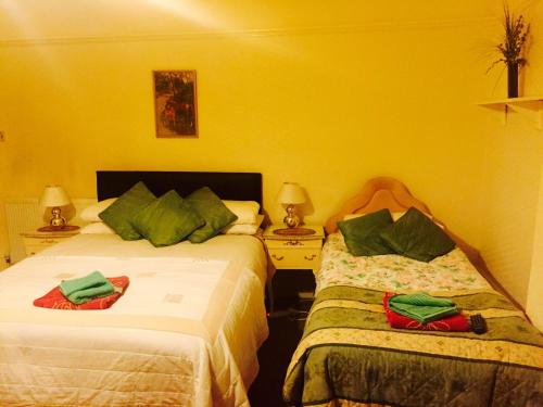 two beds in a room with yellow walls at Southend Inn Hotel - Close to Beach, Train Station & Southend Airport in Southend-on-Sea