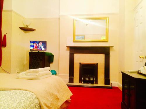 a bedroom with a fireplace and a bed with a mirror at Southend Inn Hotel - Close to Beach, Train Station & Southend Airport in Southend-on-Sea