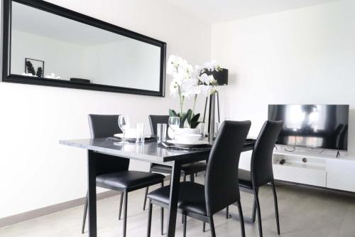 - une table à manger avec des chaises noires et un miroir dans l'établissement Frenchy by Plaza, à Serris