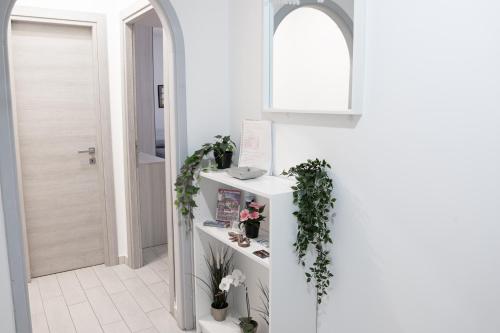 a hallway with white walls and a white counter with plants at Splendido alloggio di Noemi - Daniele Case Vacanza in Torvaianica