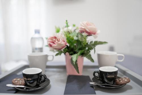 two coffee cups and a vase of flowers on a table at Splendido alloggio di Noemi - Daniele Case Vacanza in Torvaianica