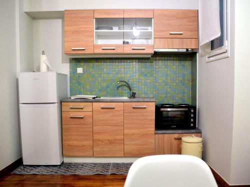 a kitchen with wooden cabinets and a white refrigerator at V for Vacation in Ioannina