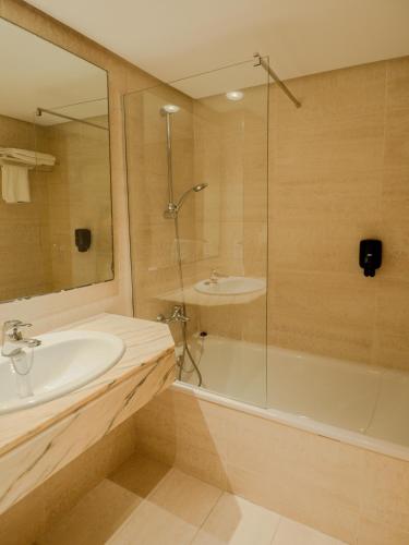 a bathroom with a tub and a sink and a shower at Hotel Santa Maria Playa in Cala Millor