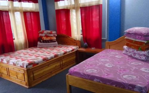 two beds in a room with red curtains at Simma Homestay By StayApart in Pedong