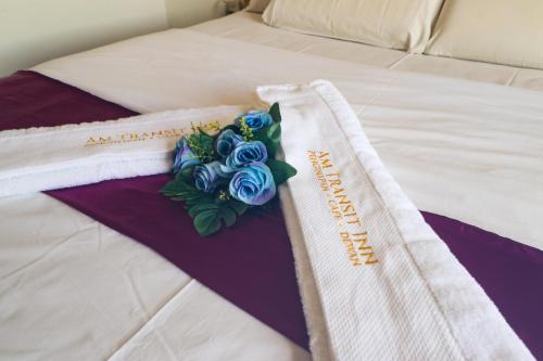 a bed with two towels and a bouquet of blue roses at AM Transit Inn Kuala Terengganu in Kuala Terengganu