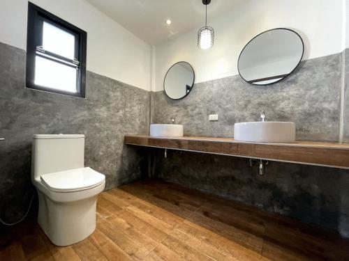 a bathroom with a toilet and two mirrors at AQUA Boutique Resort & Pool in Ko Phayam