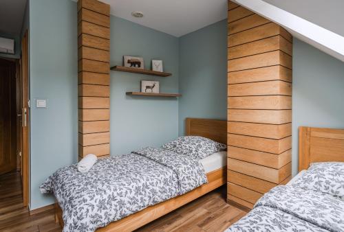 two twin beds in a bedroom with a wall of wood at Bacówka Polany in Polany