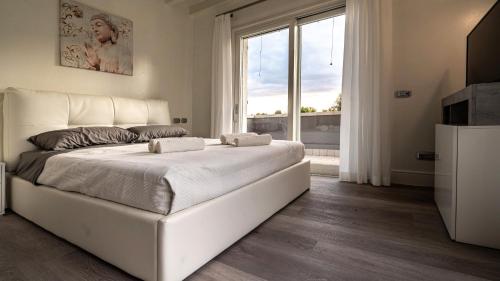 a bedroom with a large white bed and a large window at Villa Sirmione Front Lake in Sirmione