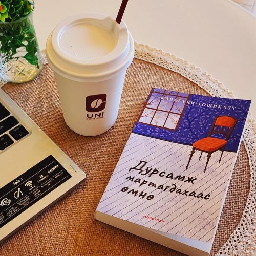 a cup of coffee next to a book and a laptop at Khangain Tugul Hotel in Tsetserleg