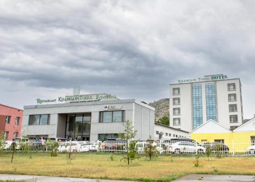 a large building with cars parked in front of it at Khangain Tugul Hotel in Tsetserleg