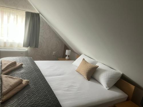 a bed with white sheets and pillows in a room at Relax Apartman in Sümeg
