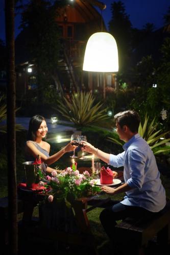 a man and woman sitting at a table with glasses at The Kirana Ungasan in Jimbaran