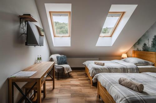 a room with two beds and a desk and two windows at Bacówka Polany in Polany