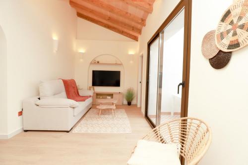 a living room with a white couch and a tv at Casa Pilara Alojamiento rural in Callosa de Segura