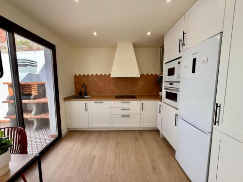 a kitchen with white cabinets and a large window at Casa Pilara Alojamiento rural in Callosa de Segura