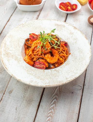 a plate of pasta with shrimp and vegetables on a table at Khangain Tugul Hotel in Tsetserleg