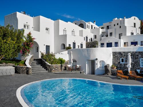 a villa with a swimming pool in front of white buildings at Finikia Memories Hotel in Oia