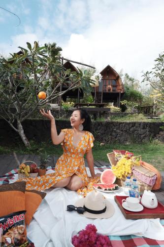 a woman sitting on a picnic blanket with an orange at The Kirana Ungasan in Jimbaran
