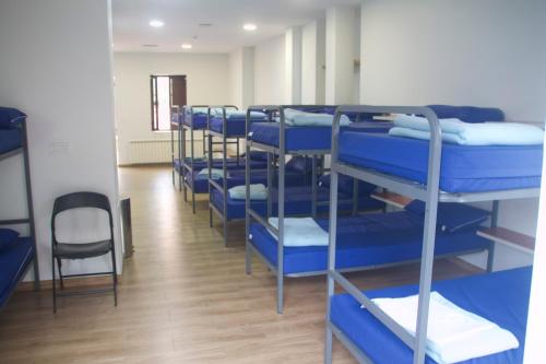 rząd niebieskich łóżek piętrowych w pokoju w obiekcie Albergue Parroquial Santiago Apostol de Redondela w mieście Redondela