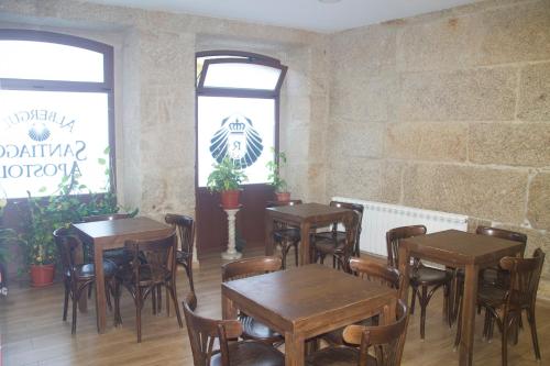 restauracja z drewnianymi stołami i krzesłami w pokoju w obiekcie Albergue Parroquial Santiago Apostol de Redondela w mieście Redondela