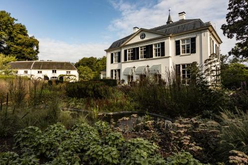 a white house in the middle of a garden at Landgoed Loenen B&B in Slijk-Ewijk