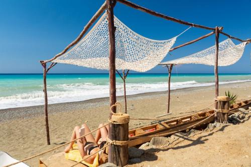 a woman laying in a hammock on the beach at Latchi Bay Apartment in Lachi