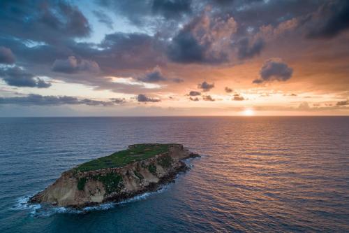 an island in the ocean with a sunset at Latchi Harbour Maisonette in Lachi