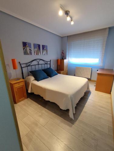 una camera da letto con un grande letto bianco con cuscini blu di apartamento de tres dormitorios con garaje y todos los servicios cerca a Burgos
