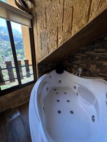 a white bath tub in a room with windows at Rokwood faraya in Ash Sha‘rah