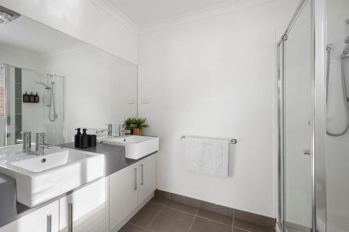 Un baño blanco con dos lavabos y una ducha. en City and Sea Retreat - Family Friendly Stay, en Marshalltown