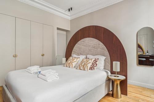 - une chambre avec un grand lit blanc et une tête de lit en bois dans l'établissement Modern apartment - 2P - Parc Monceau, à Paris