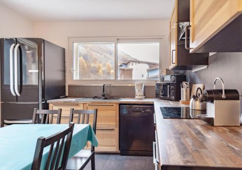 une cuisine avec une table et une grande fenêtre dans l'établissement Appart cosy au cœur de la montagne, à deux pas du télésiège, 4 CH, Tout confort, à Les Deux Alpes