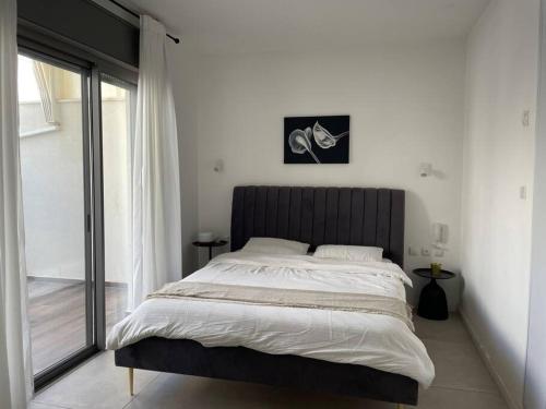 a bedroom with a large bed and a window at luxury penthouse with a jaccuzi, pool and parking, suka for Sukkot optional in H̱olon