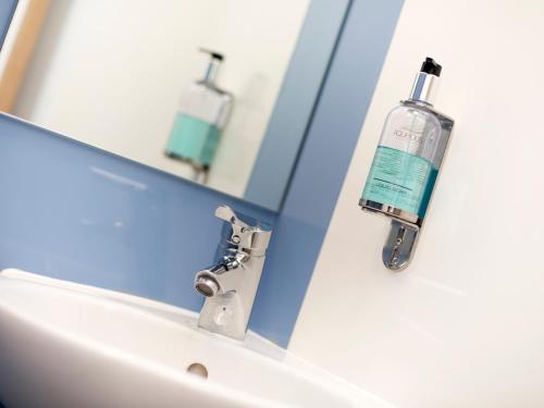um lavatório de casa de banho com uma garrafa de anti-séptico bucal num espelho em YHA Cambridge em Cambridge