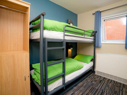 um quarto beliche com 2 beliches com almofadas verdes em YHA Cambridge em Cambridge