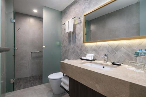 a bathroom with a sink and a toilet and a mirror at Hotel Santika Lahat in Lahat