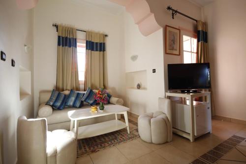 a living room with a couch and a tv at Hôtel Le Tinsouline in Zagora