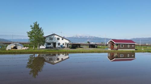 a house and a barn next to a body of water at Furano Cottage Shelter in Nakafurano