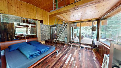 a bed in a room with wooden floors and windows at Chata v srdci lesa in Čadca