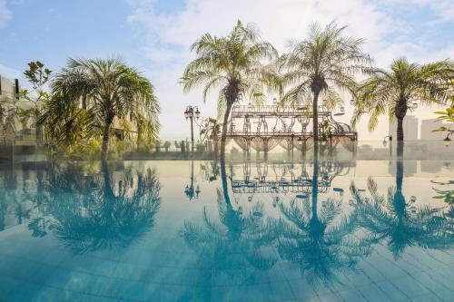 a pool of water with palm trees and a bridge at Hanoi Tirant Hotel in Hanoi