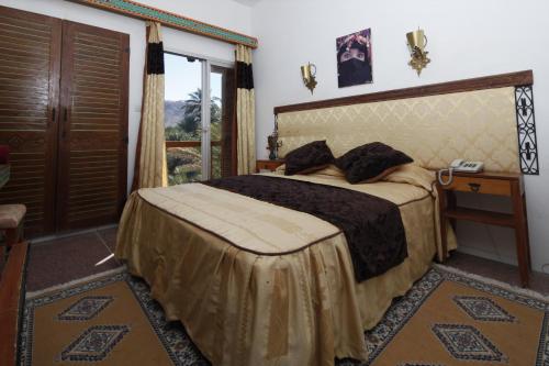 a bedroom with a bed and a window at Hôtel Le Tinsouline in Zagora