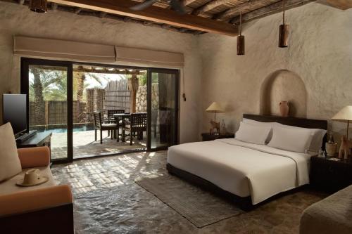a bedroom with a bed and a patio with a table at Six Senses Zighy Bay in Dibba
