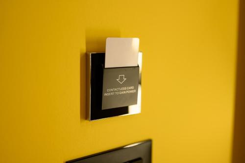 a switch on a yellow wall with a box on it at Adore Home in Tirana