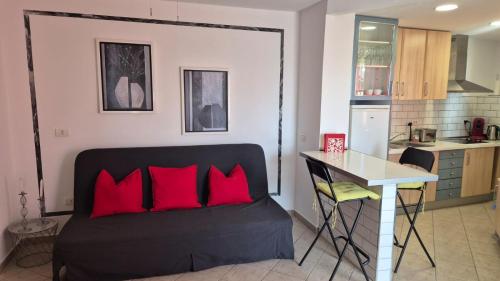 a room with a bed with red pillows and a kitchen at Apartment Puerto de Santiago in Puerto de Santiago