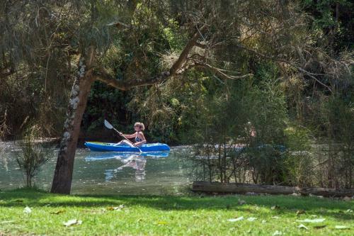 a girl in a blue kayak on a river at Seven Mile Beach Holiday Park in Gerroa