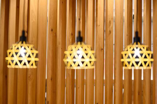 two lights are hanging on a wooden wall at Adore Home in Tirana