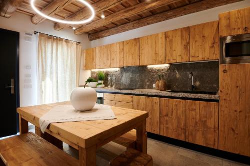 a kitchen with wooden cabinets and a table with a vase on it at Brocheta Guest House, immersa nella natura in Chies dʼAlpago