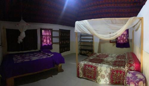 a bedroom with a bed and a canopy at Campement Courbine in Ndangane