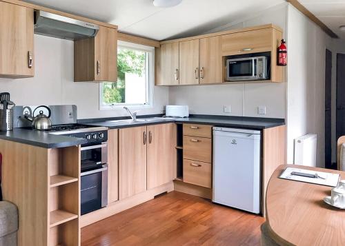 a kitchen with wooden cabinets and a table in it at Woodovis Park in Tavistock